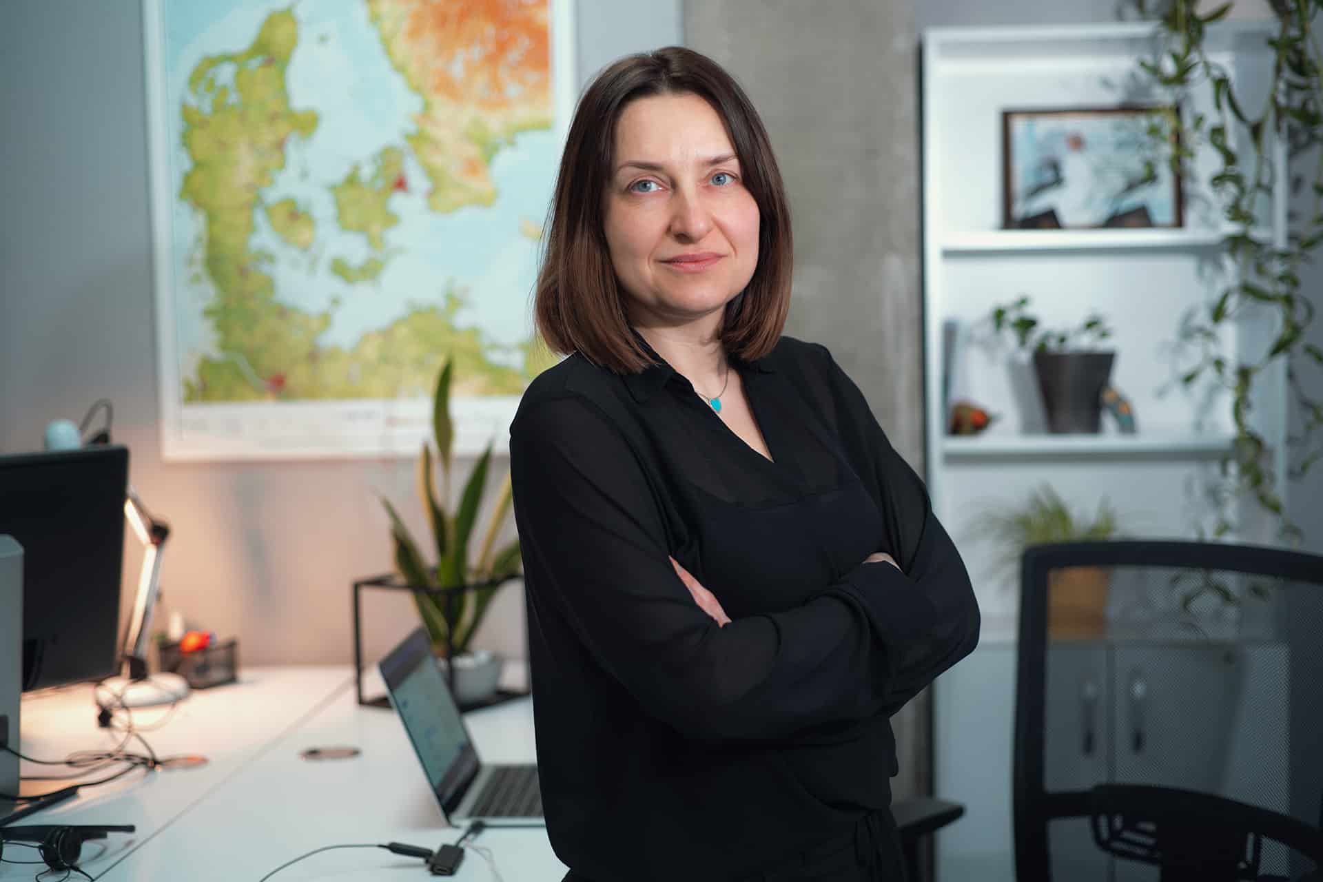 Halyna Shporlyuk steht selbstbewusst in ihrem Büro und reflektiert über ihre zehnjährige Karriereentwicklung bei Conscensia.