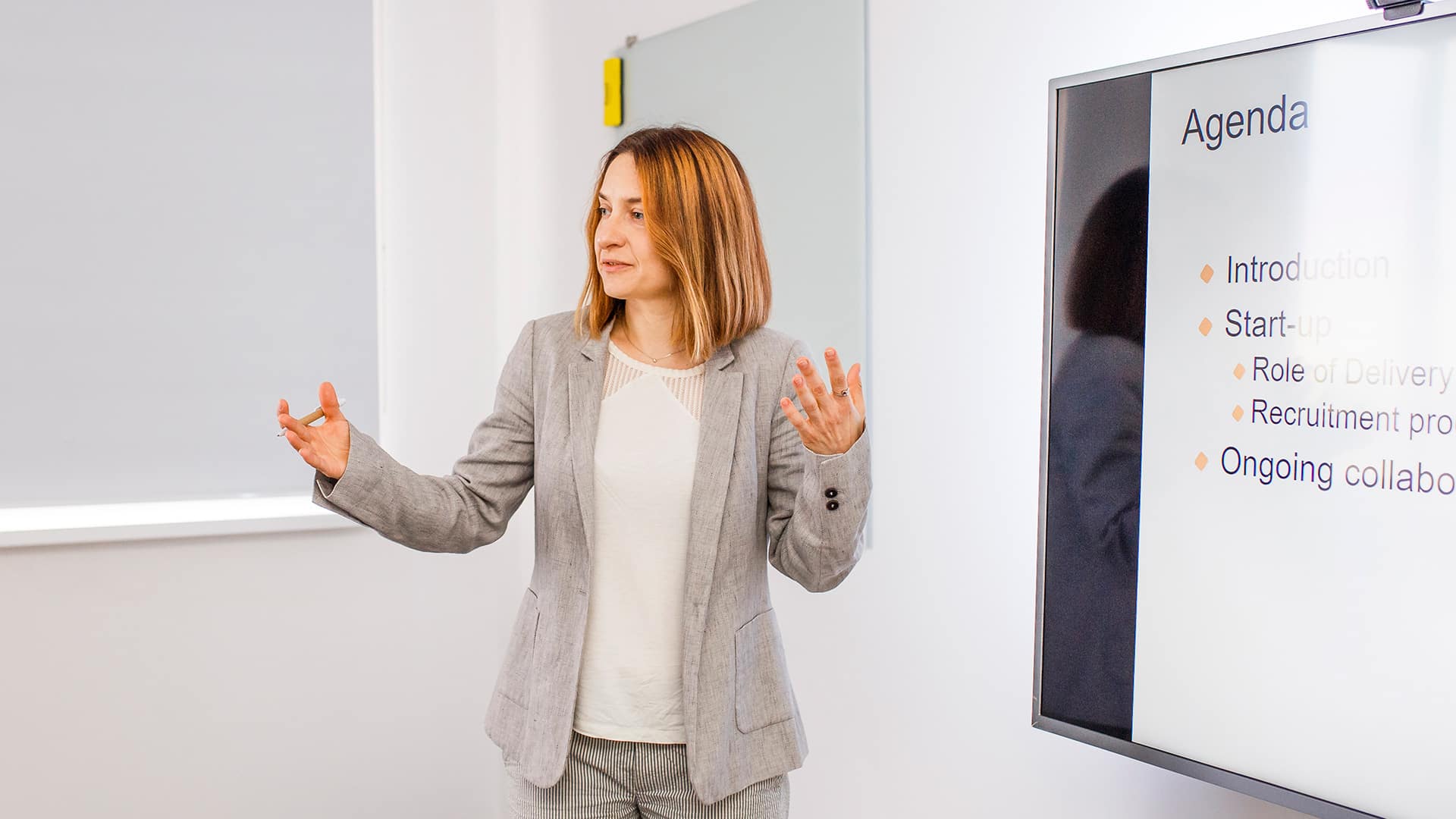 Halyna Shporlyuk gestikuliert während eines Conscensia-Meetings in Richtung des Präsentationsbildschirms.